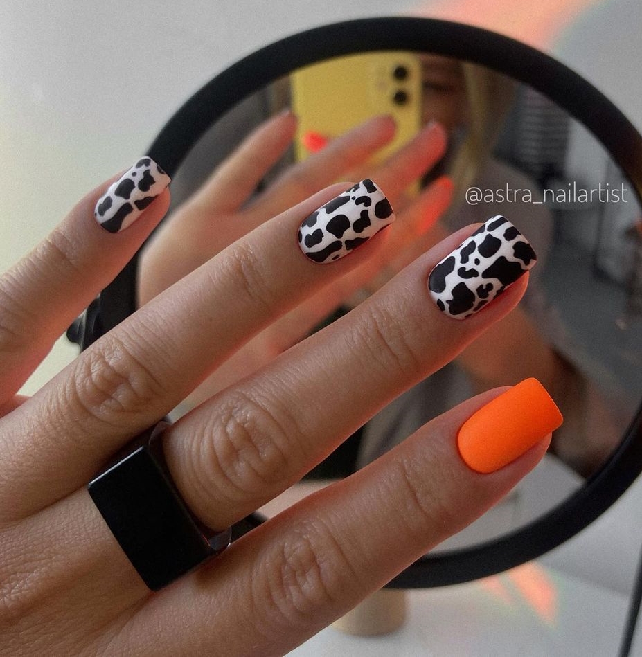 Bright Orange Nails with Black and White Cow Print Design