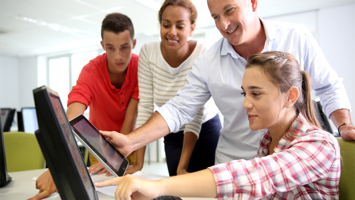 teacher and students gathered around monitor