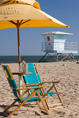 Yellow beach umbrella and chairs on the Ventura State Beach with a lifeguard tower in the background
